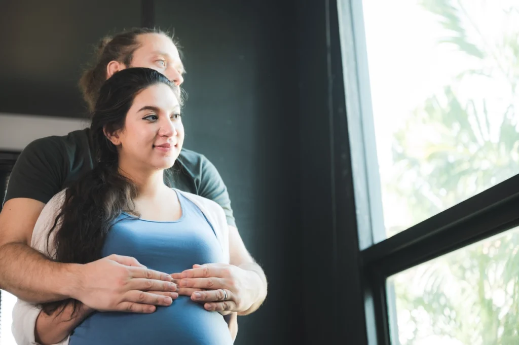 happy pregnant couple placing baby shoes on woman 2023 11 27 05 04 33 utc
